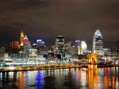 the city skyline is lit up at night with lights reflecting in the water and buildings on both sides