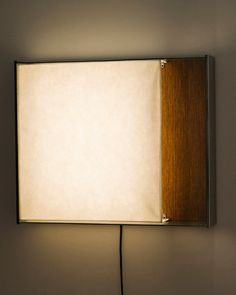 a light that is on the side of a wall with a wooden frame and white paper