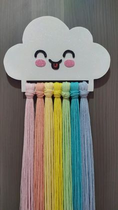 a white cloud with rainbow tassels hanging from it's side on a wooden wall