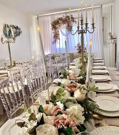 a long table with white plates and flowers on it