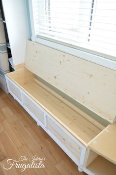 a white bench sitting in front of a window on top of a hard wood floor