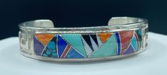 This bracelet is 925 sterling silver featuring natural turquoise, Shell, lapis, denim lapis, black onyx, coral and Sugilite  Made by famous  Navajo artist Rick Tolino Artisan Multicolor Bracelets With Inlay, Multicolor Artisan Bracelet With Inlay, Multicolor Artisan Inlay Bracelets, Multicolor Sterling Silver Bracelets With Inlay, Multicolor Handmade Cuff Bracelet Collectible, Multicolor Sterling Silver Bracelet With Inlay, Handmade Multicolor Cuff Bracelet Collectible, Southwestern Multicolor Bracelets With Inlay, Artisan Multicolor Cuff Bracelet With Inlay