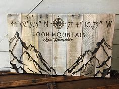 a wooden sign that says loon mountain with mountains painted on the front and back