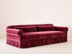 a red velvet couch sitting on top of a white floor