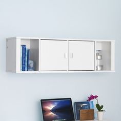 a laptop computer sitting on top of a desk next to a white shelf filled with books