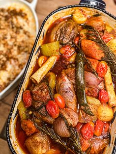 a casserole dish with vegetables and meat in it on a wooden table next to other dishes