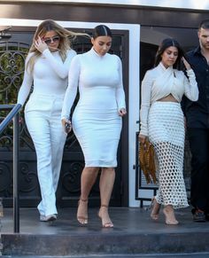 two women in white outfits are walking down the steps with one woman on her cell phone