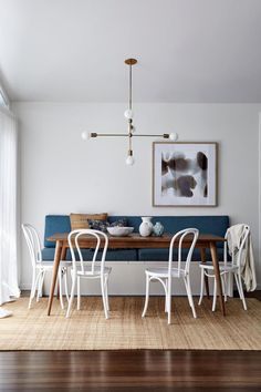 a dining room table with white chairs and a blue couch