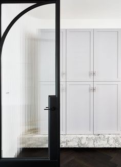 a room with white cupboards and marble flooring in front of a black door