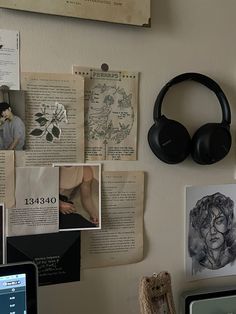 a wall covered in pictures and headphones next to a laptop computer on top of a desk