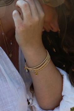 Our Golden Beaded Bracelet is a simple yet radiant addition to any fit representing strength, abundance, and happiness. High-quality 14k Goldfilled beads will last, won't tarnish, and will shine all night long. Choose between one bracelet or layer with our set of two, or stack of three. Golden Beaded Bracelet is handcrafted with 3mm smooth 14k Goldfilled beads on a strong elastic cord. Signature MB gold charm. Each piece is handmade delicately with love and care. All Bracelets are unique and special, variation in color and inclusions in the gemstones are natural. Please take off when swimming, showering, and during hot yoga as water can damage thread. Bathe in moonlight regularly to renew crystals. Enjoy!Light & Love! Friendship Bangle Jewelry With Tiny Beads, Friendship Bangle With Tiny Beads, Minimalist Hand-strung Beaded Bracelets In 14k Gold Filled, Minimalist Hand-strung 14k Gold Filled Beaded Bracelets, Spiritual Gold Bracelet With Round Beads, Adjustable Gold Single Strand Beaded Bracelet, Spiritual Jewelry With Tiny Round Beads, Everyday Gold Single Strand Pearl Bracelet, Everyday Gold Round Crystal Bracelet