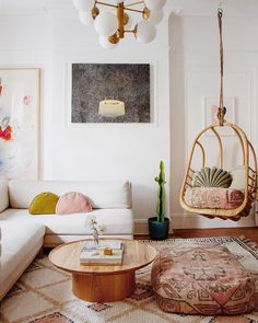 a living room filled with furniture and art on the walls, including a hanging chair