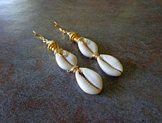 "Sea Shell Earrings, Beach Jewelry, Triple Cowrie Shell Earrings, Cowry Shells, Ethnic Dangle Earrings, African Earrings Double Cowrie Shell Dangle Earrings should definitely be in your jewelry wardrobe. This three row tier aligns perfectly well with the boldness of of gold to compliment, Approx 3.5\" length, copper ear wires. Cowrie shells were the most popular currency within Africa. Pictures of cowrie shells adorned cave walls. The Egyptians considered them to be magical agents and also used Africa Pictures, Cowrie Shell Earrings, Sea Shell Earrings, Cowry Shell, Earrings Beach, African Earrings, Cowrie Shell, Shell Earrings, Beach Jewelry