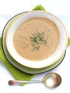 a white bowl filled with soup on top of a green napkin next to a spoon