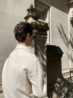 a man sitting on a bench in front of a building with a water fountain behind him