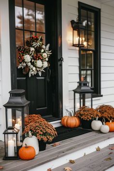 some pumpkins and candles are sitting on the steps outside of a white house with black doors