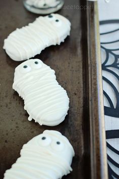 three cookies with white frosting decorated like ghost faces