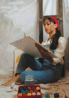 a young woman sitting on top of a bed holding a clipboard