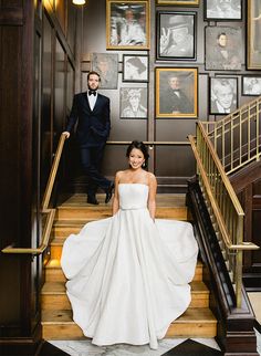 the bride and groom are posing on the stairs in front of their wedding portraits at the hotel