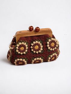 a crocheted purse with wooden handle and beaded flowers on the front, sitting on a white surface