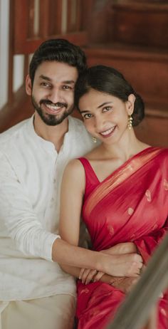 a man and woman sitting next to each other in red sari on the stairs