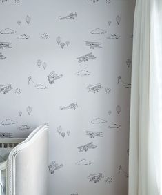 a baby's room with a crib and wallpaper featuring hot air balloons