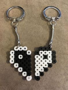 two keychains made out of legos and black and white beads are sitting on the floor