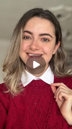 a woman in a red sweater holding up a chocolate lollipop to her face