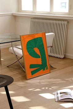 an orange and green poster sitting on top of a hard wood floor next to a radiator