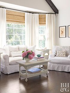 a living room filled with white furniture and flowers in vases on the coffee table