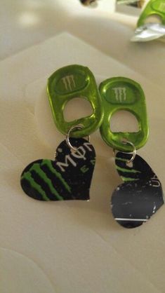 two pairs of green and black heart shaped earrings on a white surface with the word mom written in large letters