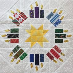 a quilted wall hanging with different colored blocks and stars in the center, on top of white polka dotty fabric