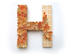 the letter h is made out of paper and decorated with orange swirly designs on it