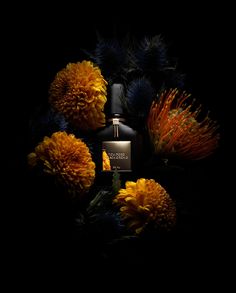 the perfume bottle is surrounded by flowers and leaves on a black background with dark lighting