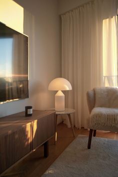 a living room with a large television mounted on the wall next to a white chair