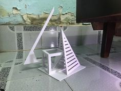 a white sculpture sitting on top of a tiled floor next to a wooden table and chair