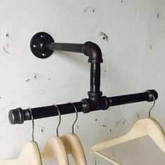 three wooden hangers are hanging on the wall next to each other, with two black handles and one white hanger