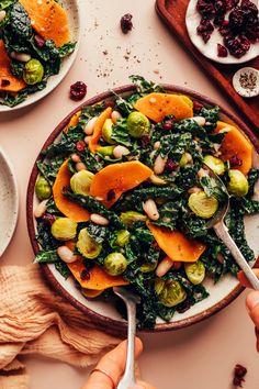 a bowl filled with greens and oranges on top of a table next to other dishes