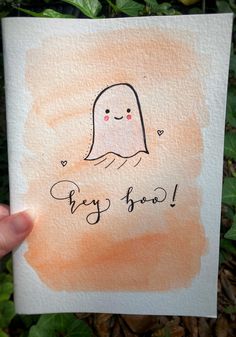 a hand holding up a card with a ghost on it and the words hey boo written in cursive ink