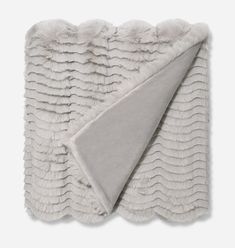 the blanket is folded on top of it and has a gray thrower in front of it