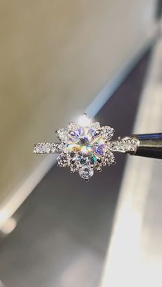 a diamond ring being held by a pair of tongs