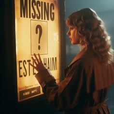 a woman standing next to a sign that reads missing? estham on the wall