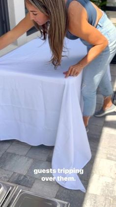 a woman leaning over a table with a white cloth on it