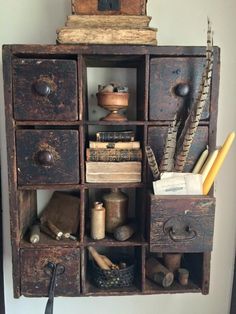 an old wooden shelf with many drawers and items in it on top of a wall