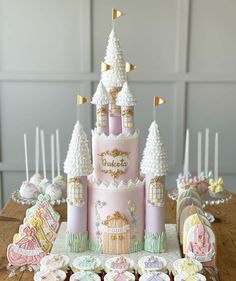 a pink and gold princess castle cake with cupcakes on the table next to it