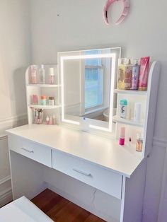 a white desk topped with a mirror and a shelf filled with personal care items next to a window