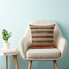 a chair with a pillow on it next to a small table and potted plant