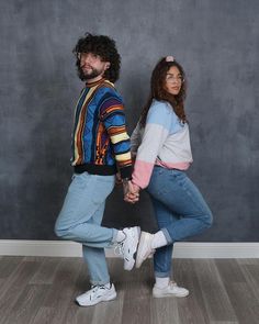 a man and woman holding hands while standing on the floor in front of a wall