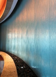 a curved wooden bench sitting next to a wall