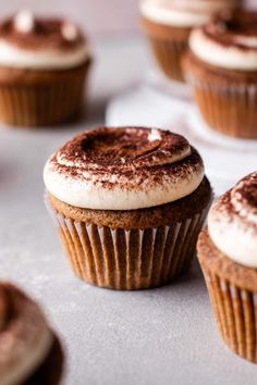 several cupcakes with frosting and sprinkles sitting on a table